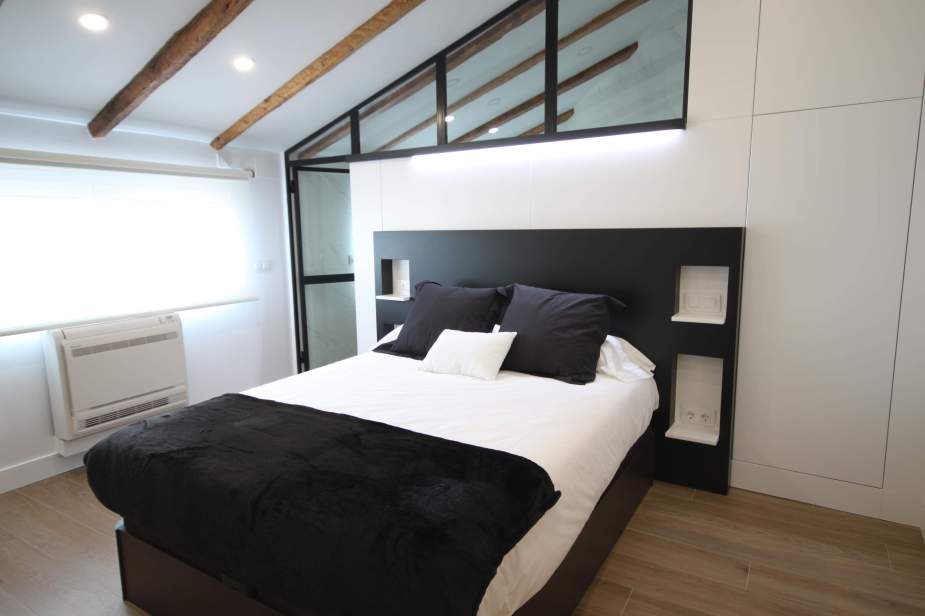 Dormitorio con cabecero de obra y separador de baño